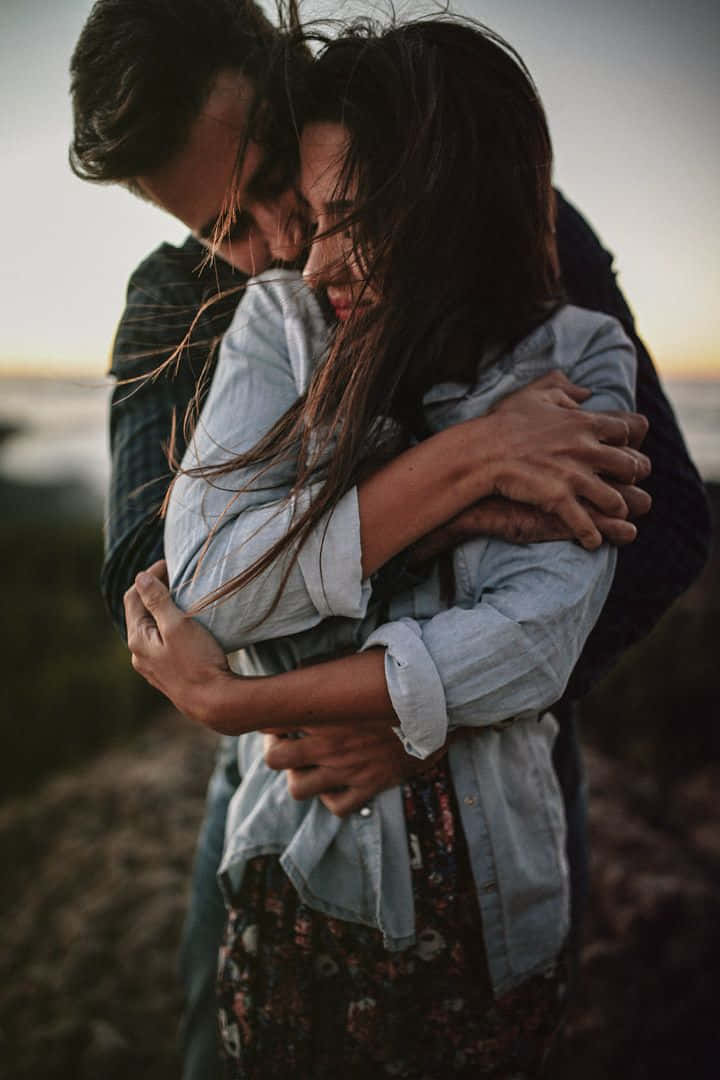 A Couple Hugging On A Hillside