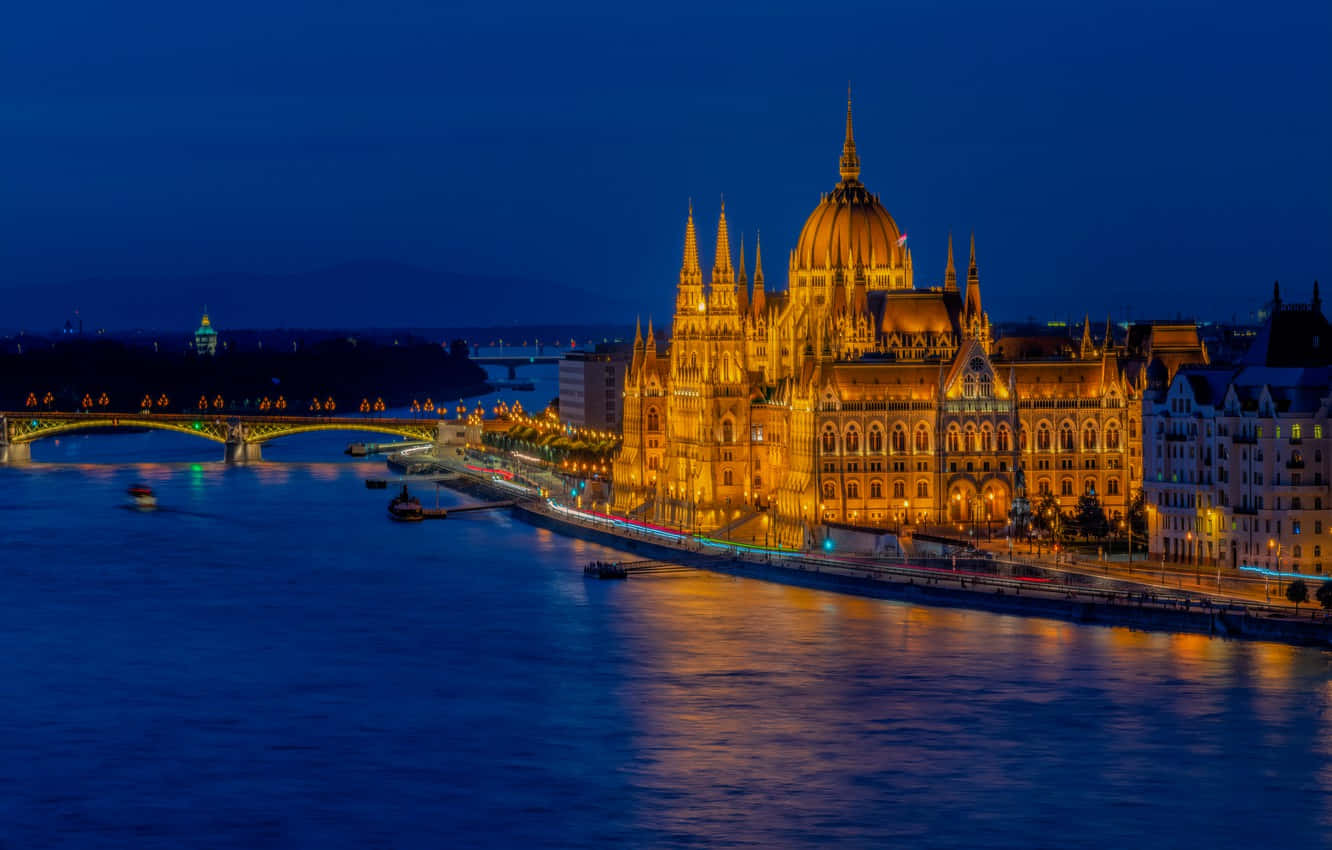 Edificiodel Parlamento Húngaro Y Puente Por La Noche Fondo de pantalla
