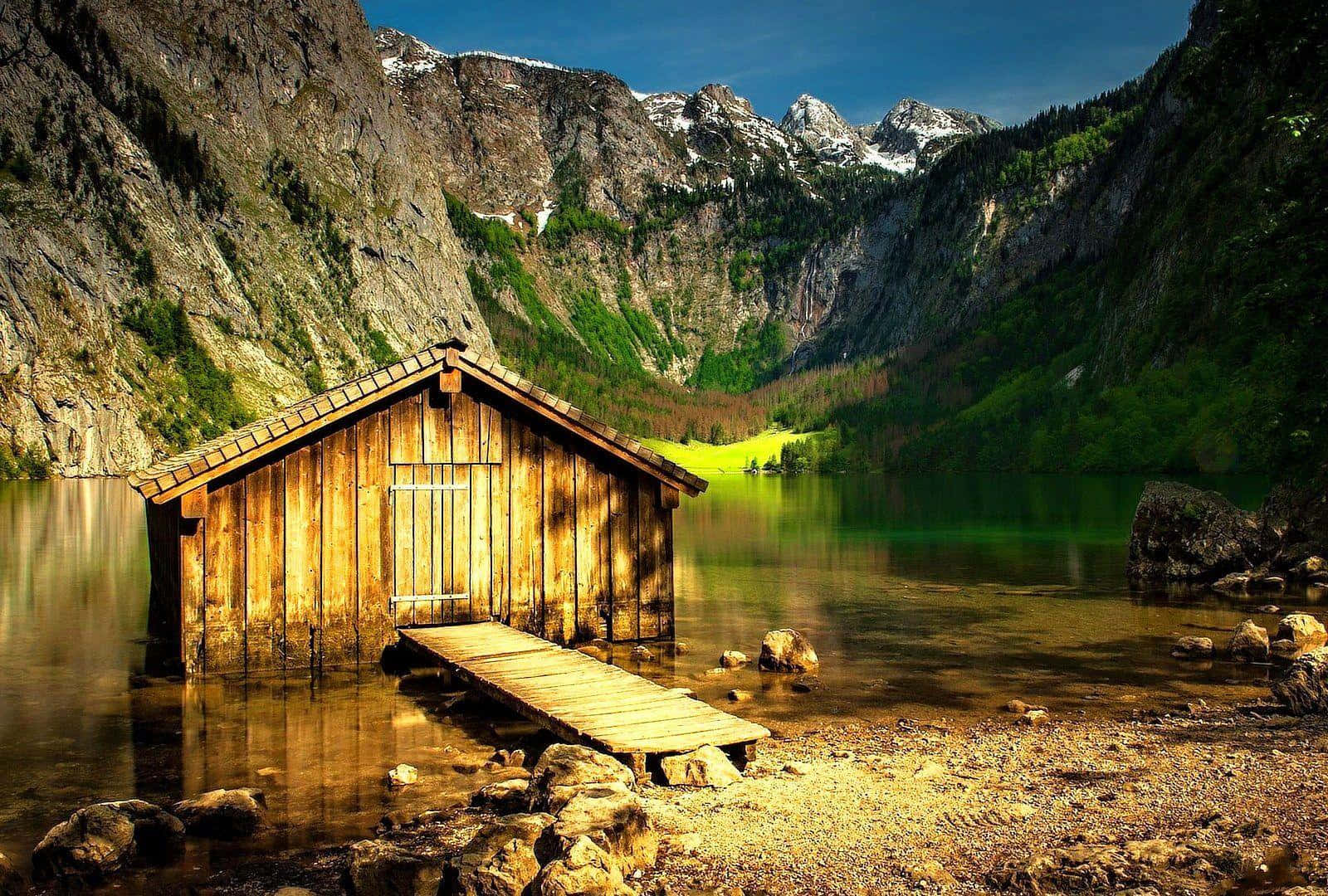A Wooden Cabin Sits On The Shore Of A Lake