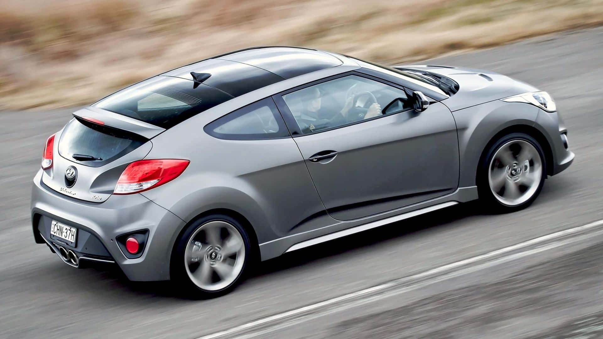 Sleek Hyundai Veloster in motion on a scenic drive Wallpaper