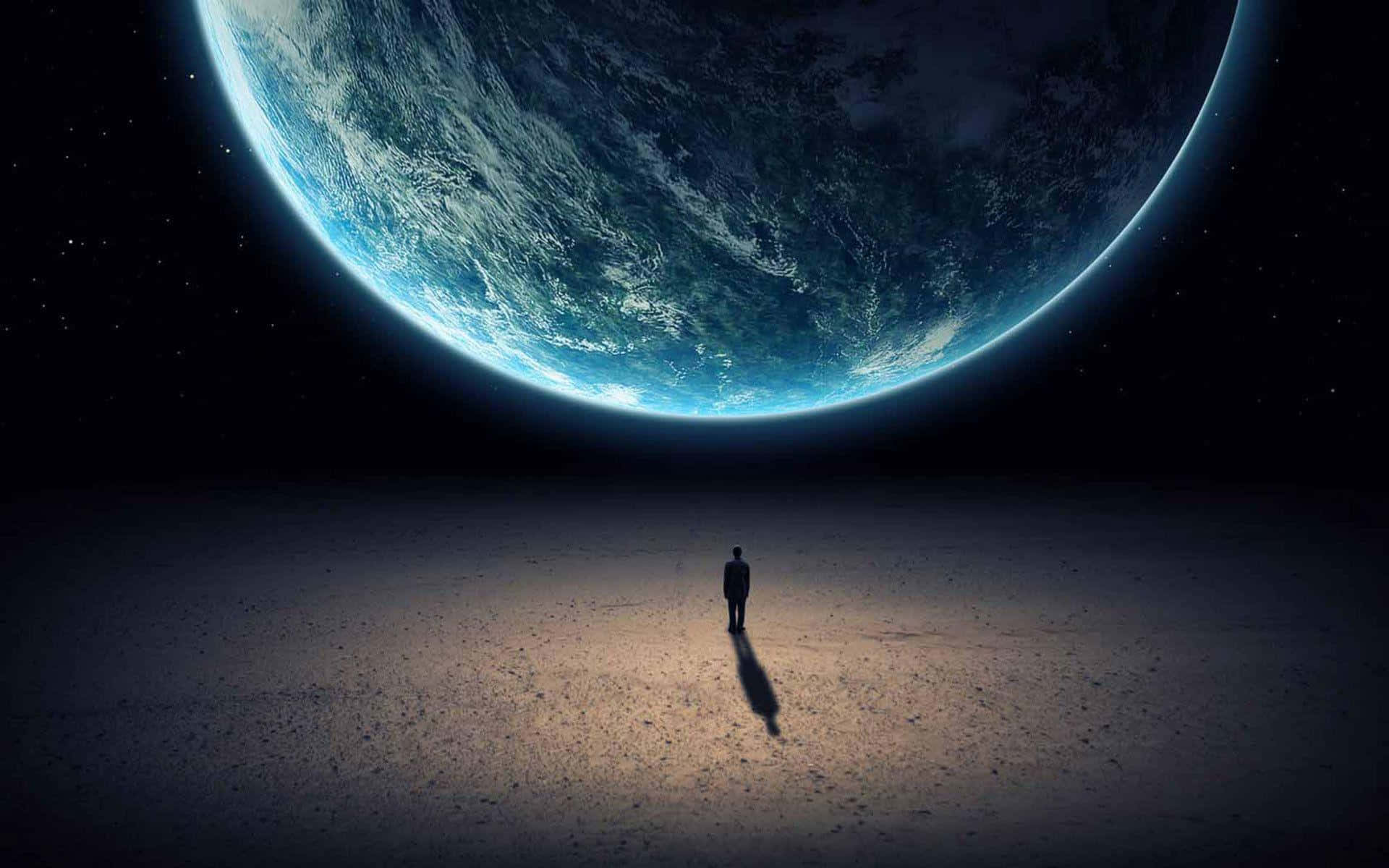 A Man Standing In The Desert With The Earth In The Background Wallpaper