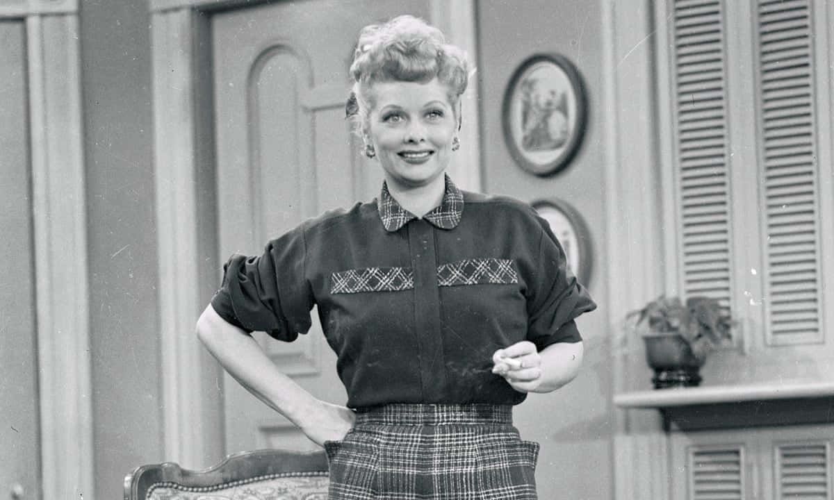 A Woman In Plaid Skirt And Shirt Standing In Front Of A Couch Wallpaper