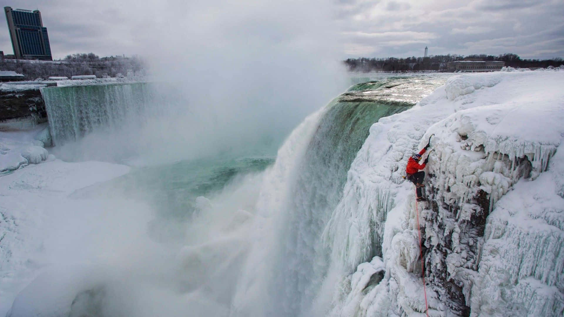 Ice Climber Ascending a Frozen Waterfall Wallpaper