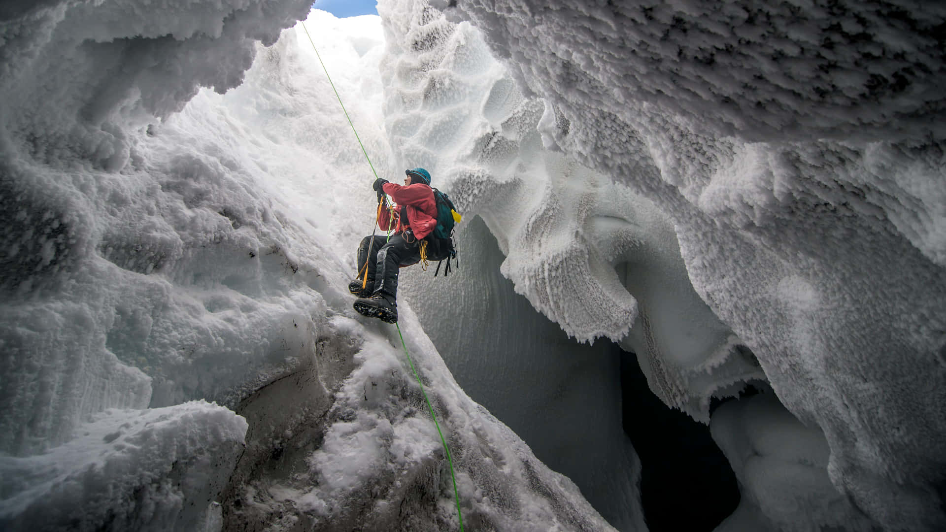 A daring ice climber ascending a frozen waterfall Wallpaper