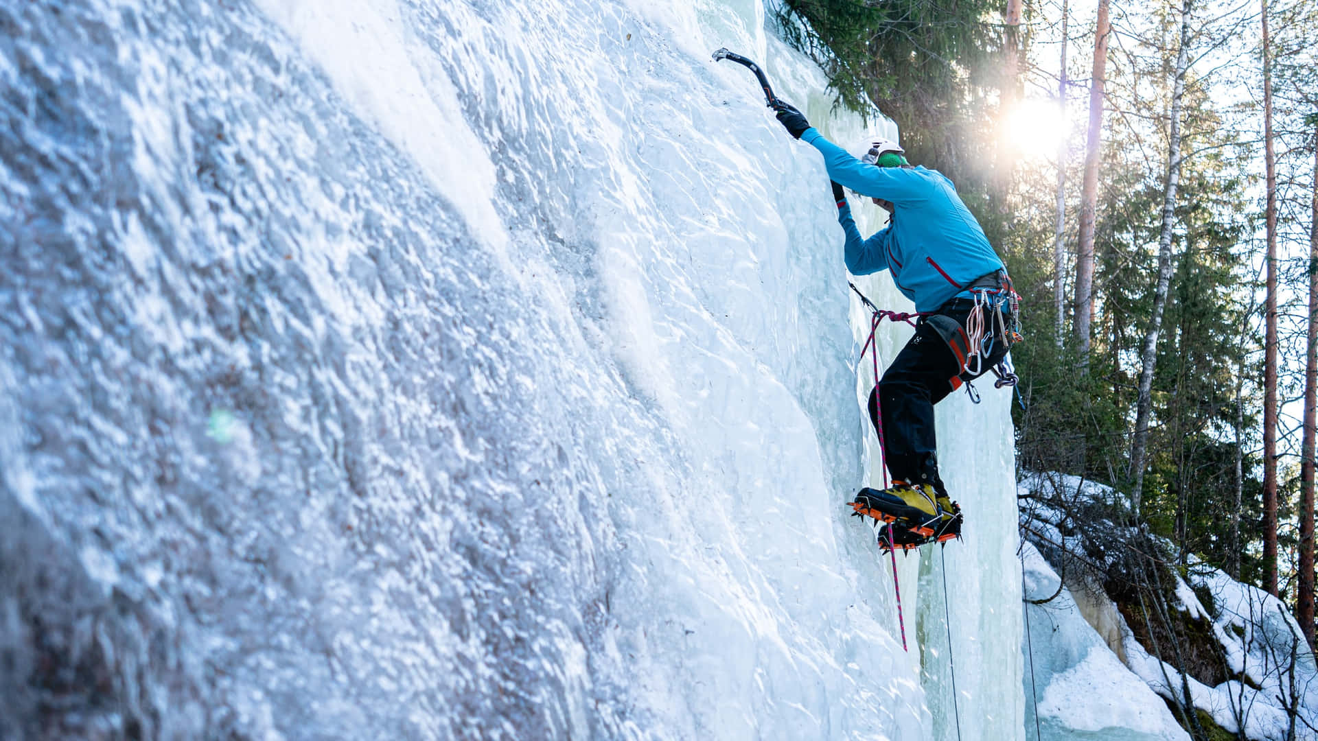 Ice Climber Scaling a Frozen Waterfall Wallpaper
