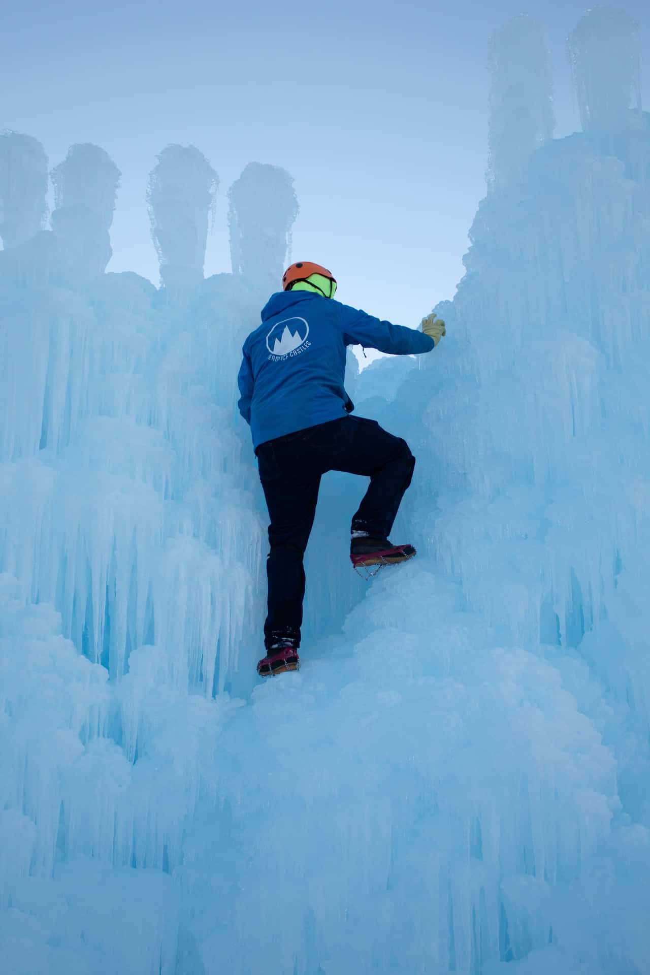 Caption: Expert ice climber ascends a frozen waterfall Wallpaper