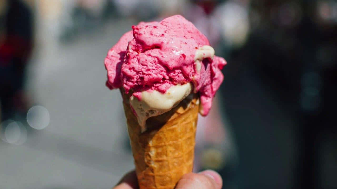 A Person Holding Up A Pink Ice Cream Cone