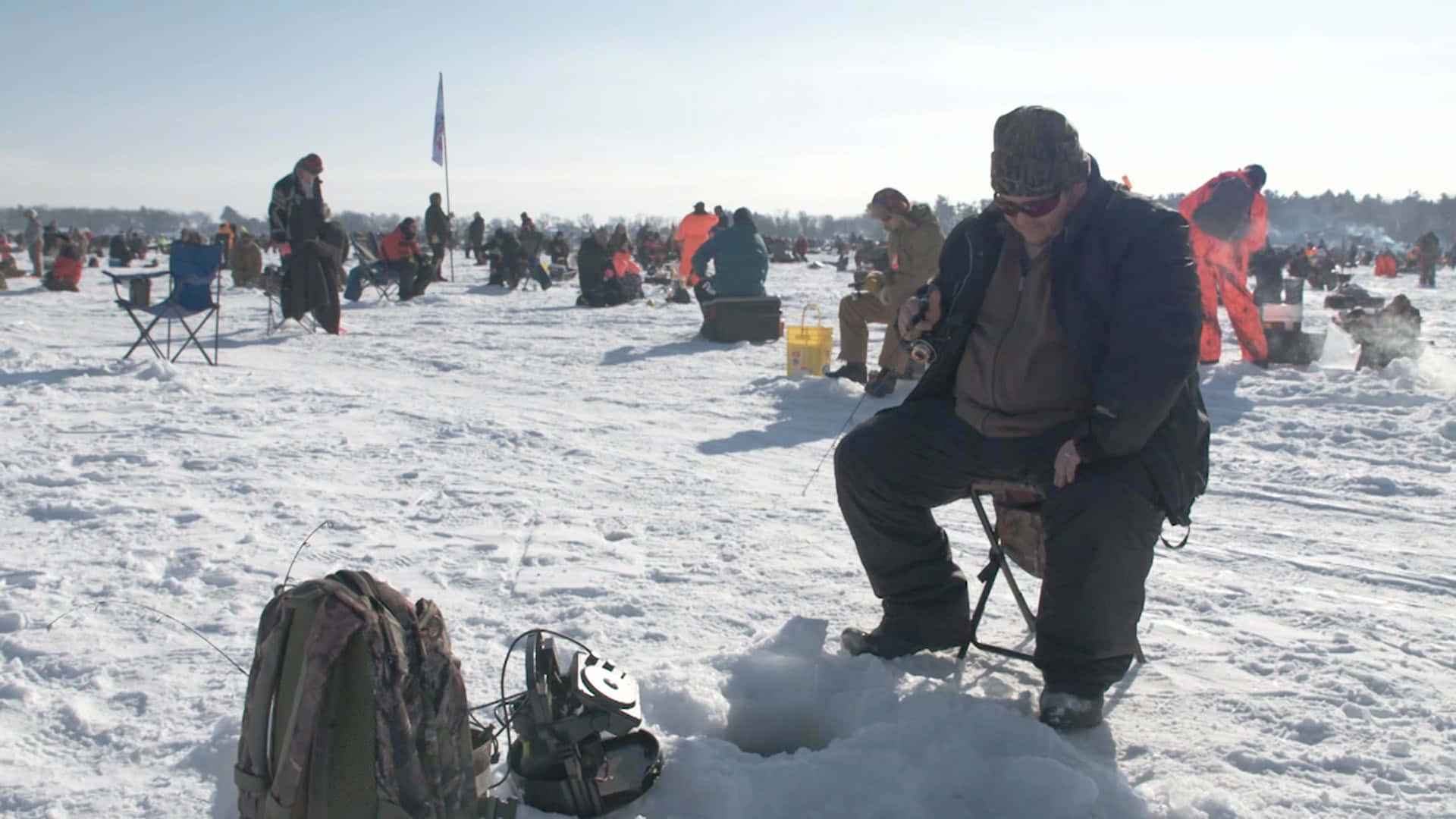 Angler Enthusiastically Ice Fishing on a Frozen Lake Wallpaper