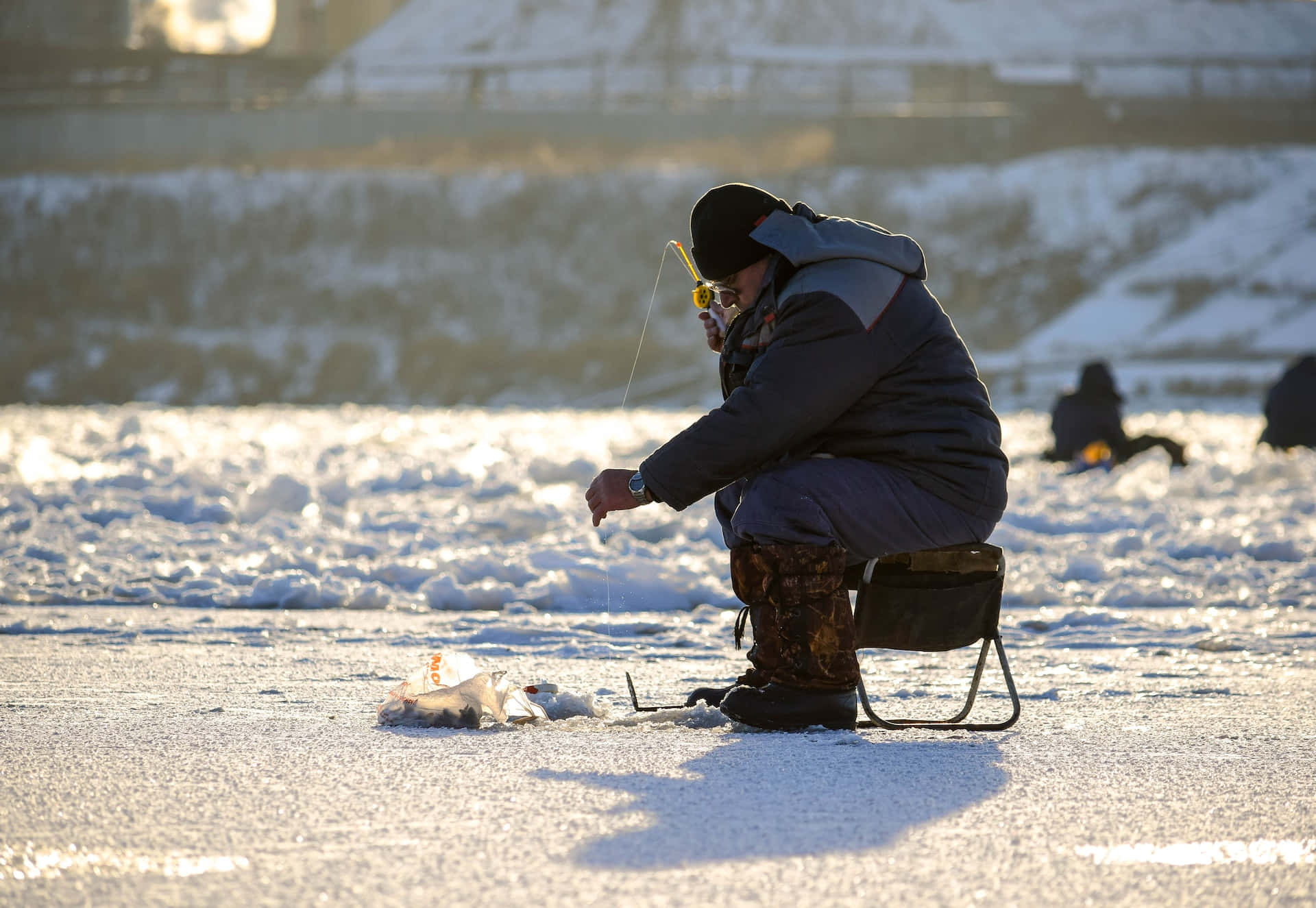 A serene ice fishing adventure on a frozen lake Wallpaper