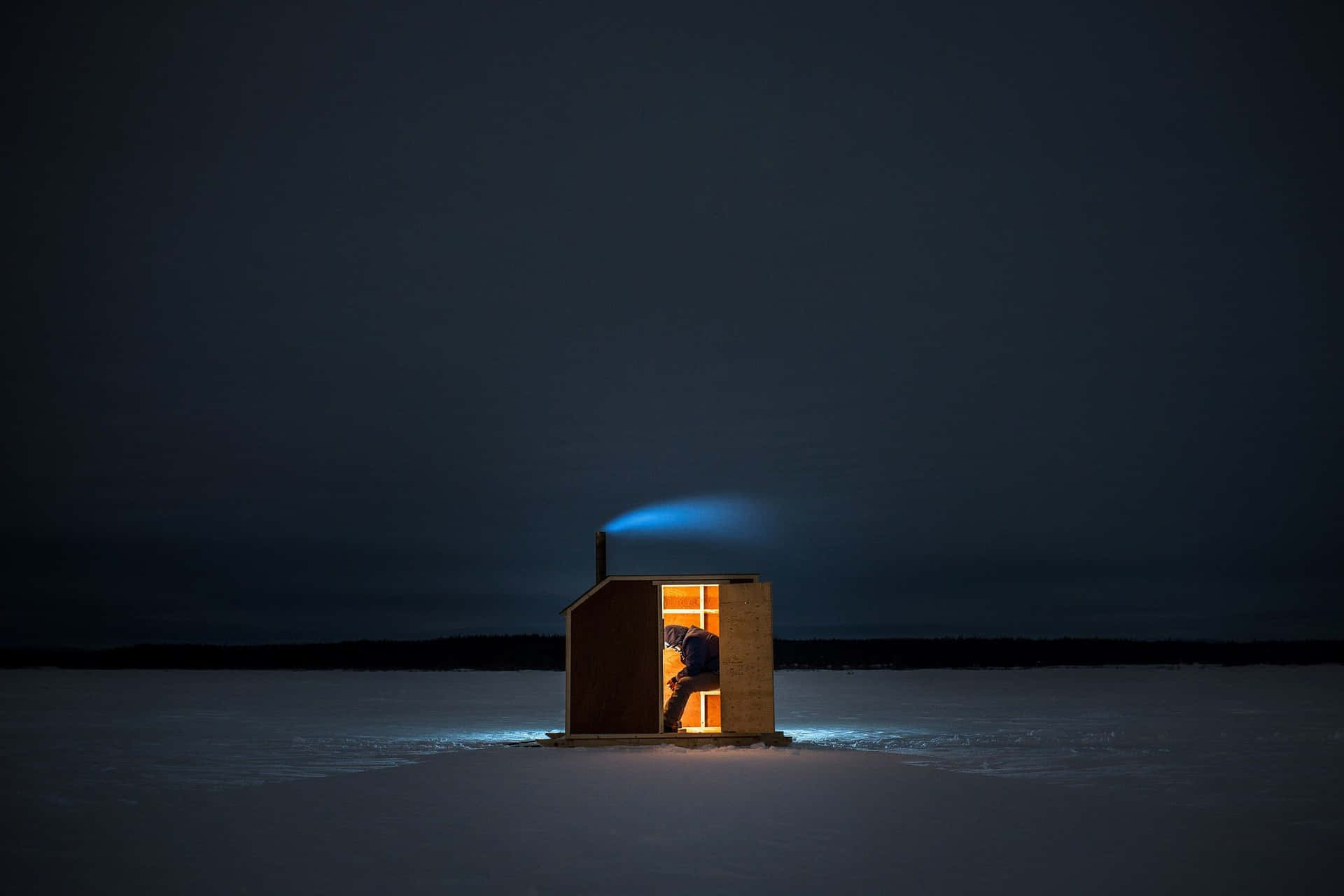 Ice fishing on a frozen lake with a snowy background Wallpaper