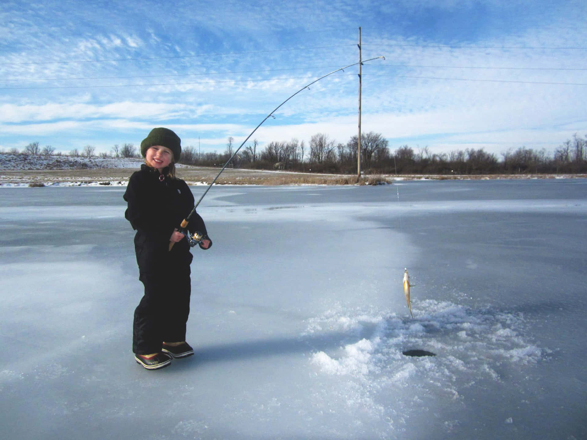 Caption: Ice fishing adventures in snowy winter landscape Wallpaper