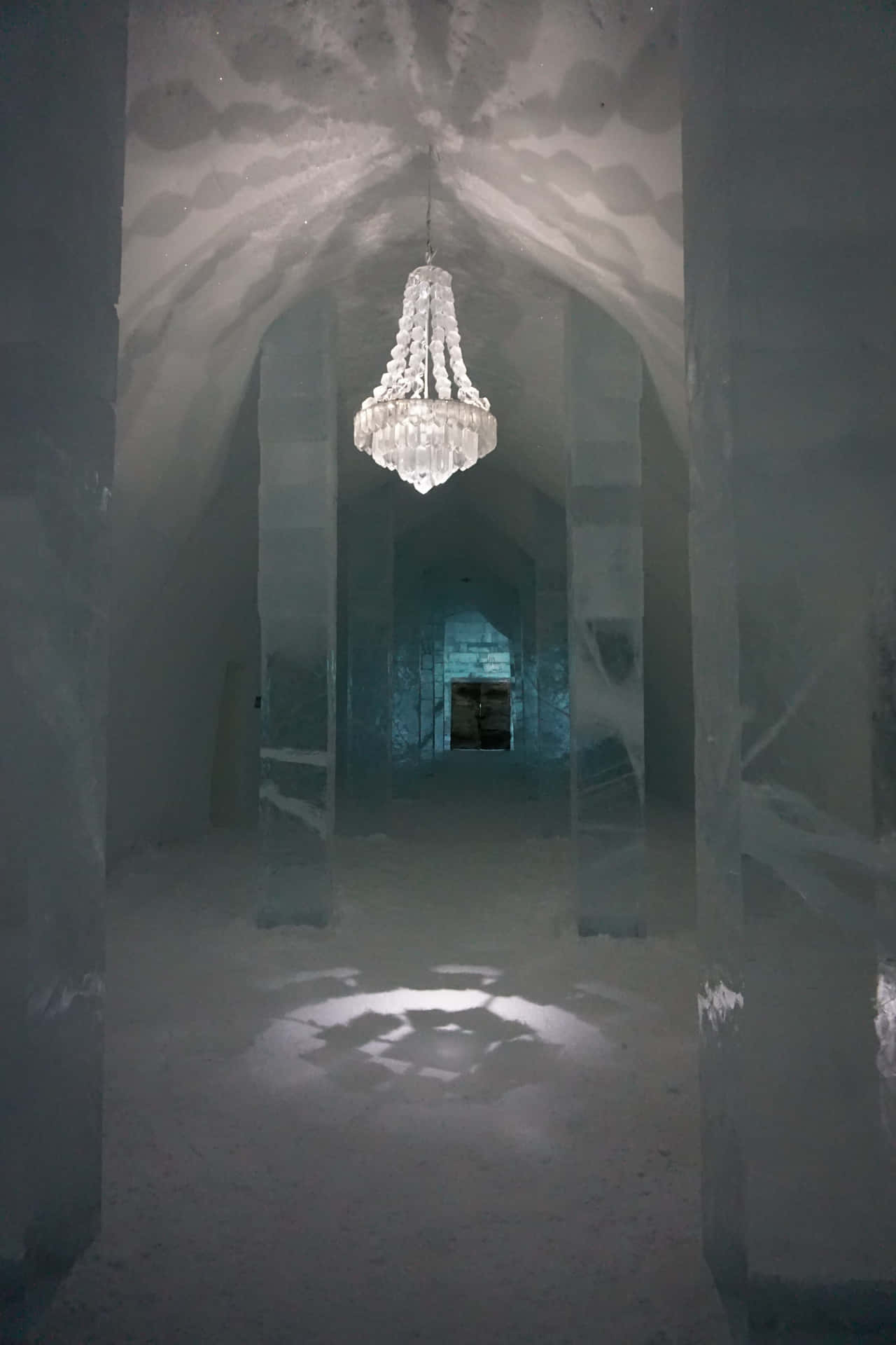 A magnificent ice hotel room, decorated with intricate ice sculptures and illuminated by a soft blue light. Wallpaper