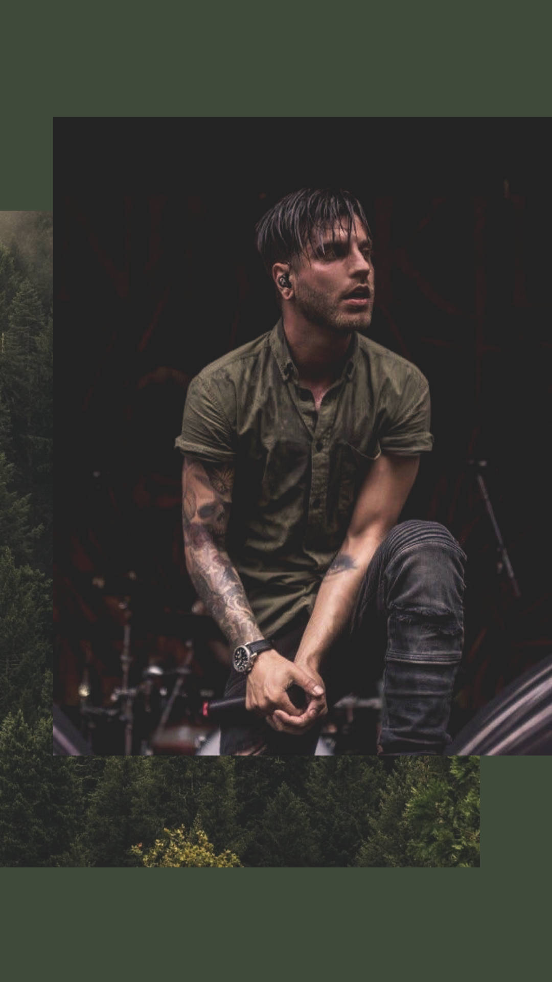 A Man With Tattoos Sitting On A Stage In The Forest Wallpaper