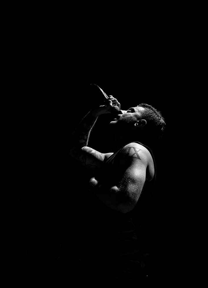 A Man Singing Into A Microphone In The Dark Wallpaper