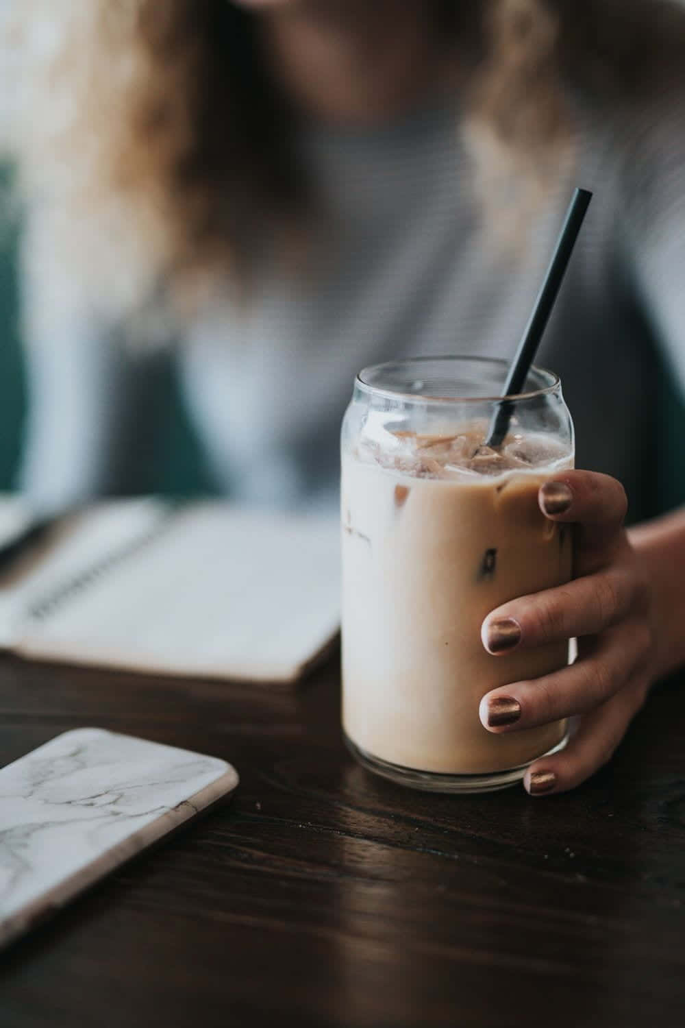 A Woman Holding A Glass Of Iced Coffee