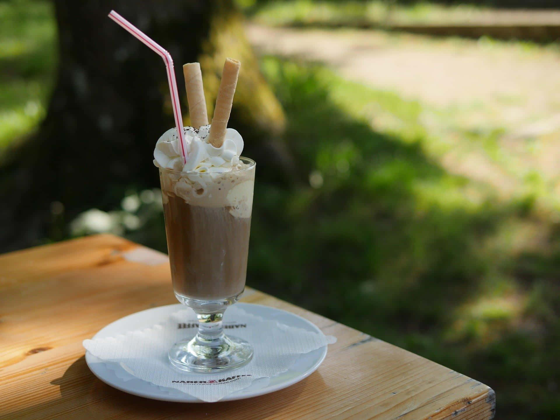 A Chocolate Drink With A Straw On A Wooden Table