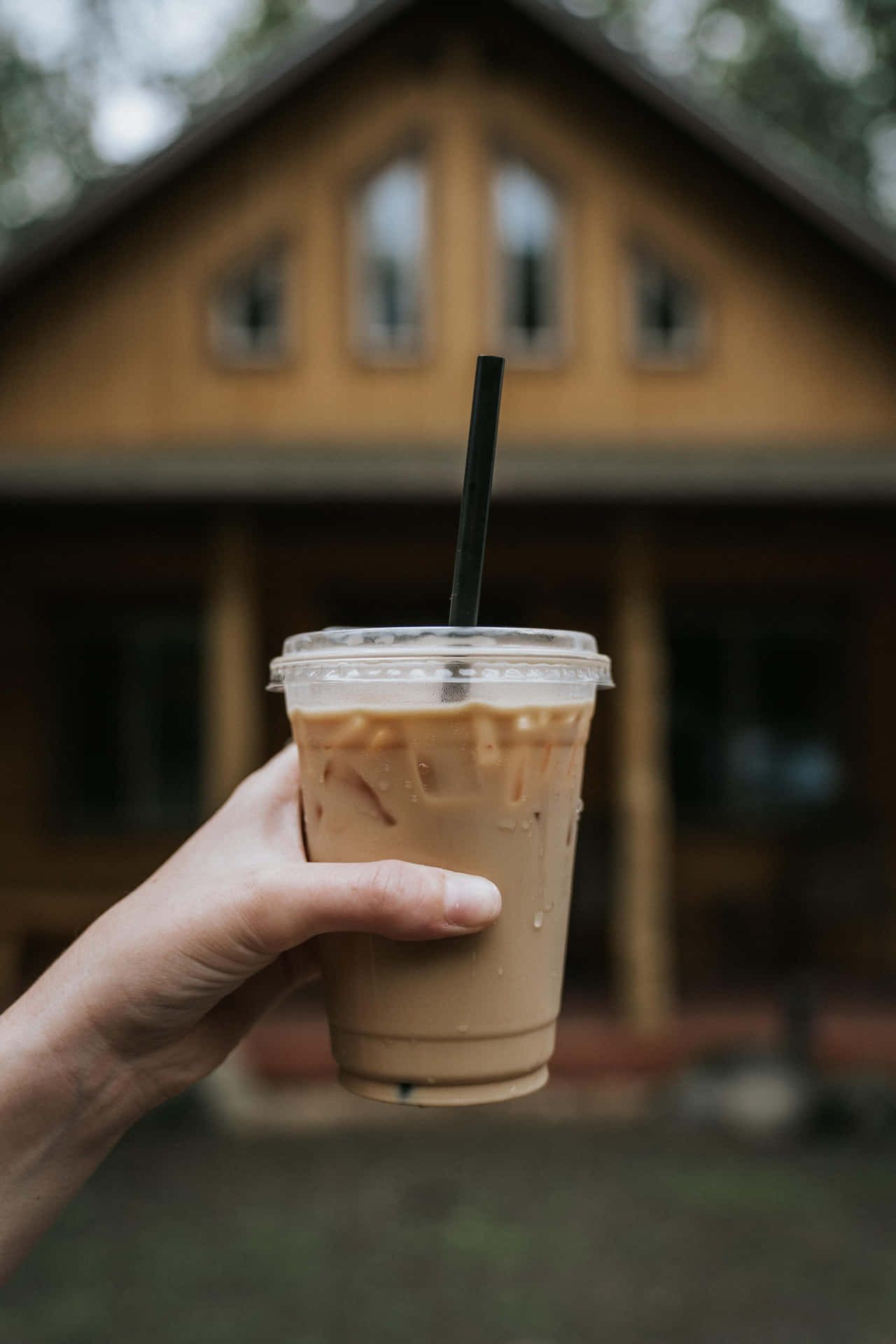 A Woman Holding A Cup Of Coffee In Front Of A Cabin