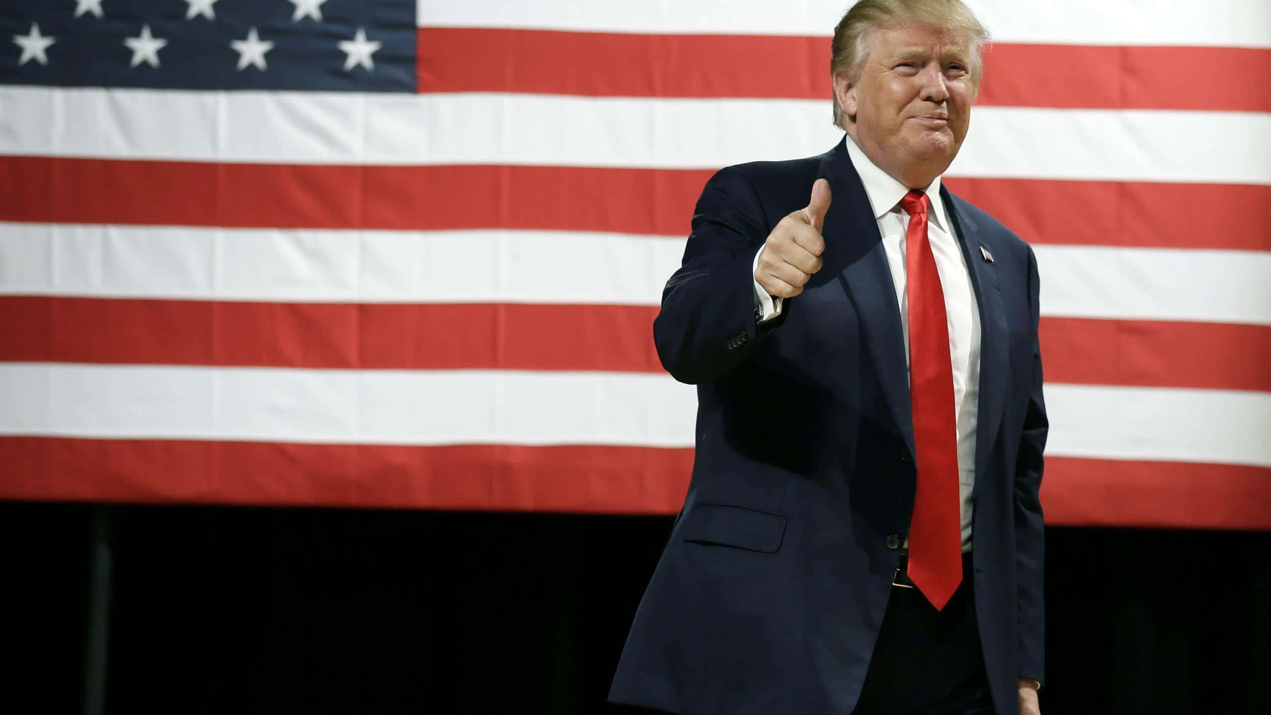 Ilpresidente Donald Trump Che Pronuncia Un Discorso Con La Bandiera Americana Sullo Sfondo.