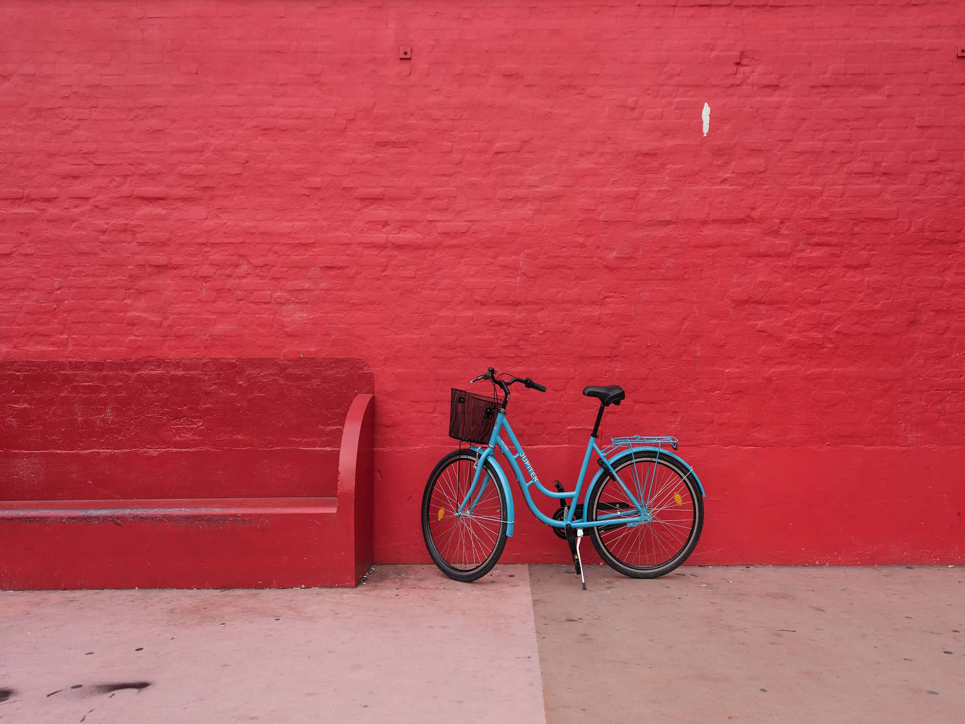 a blue bicycle leaning against a red wall