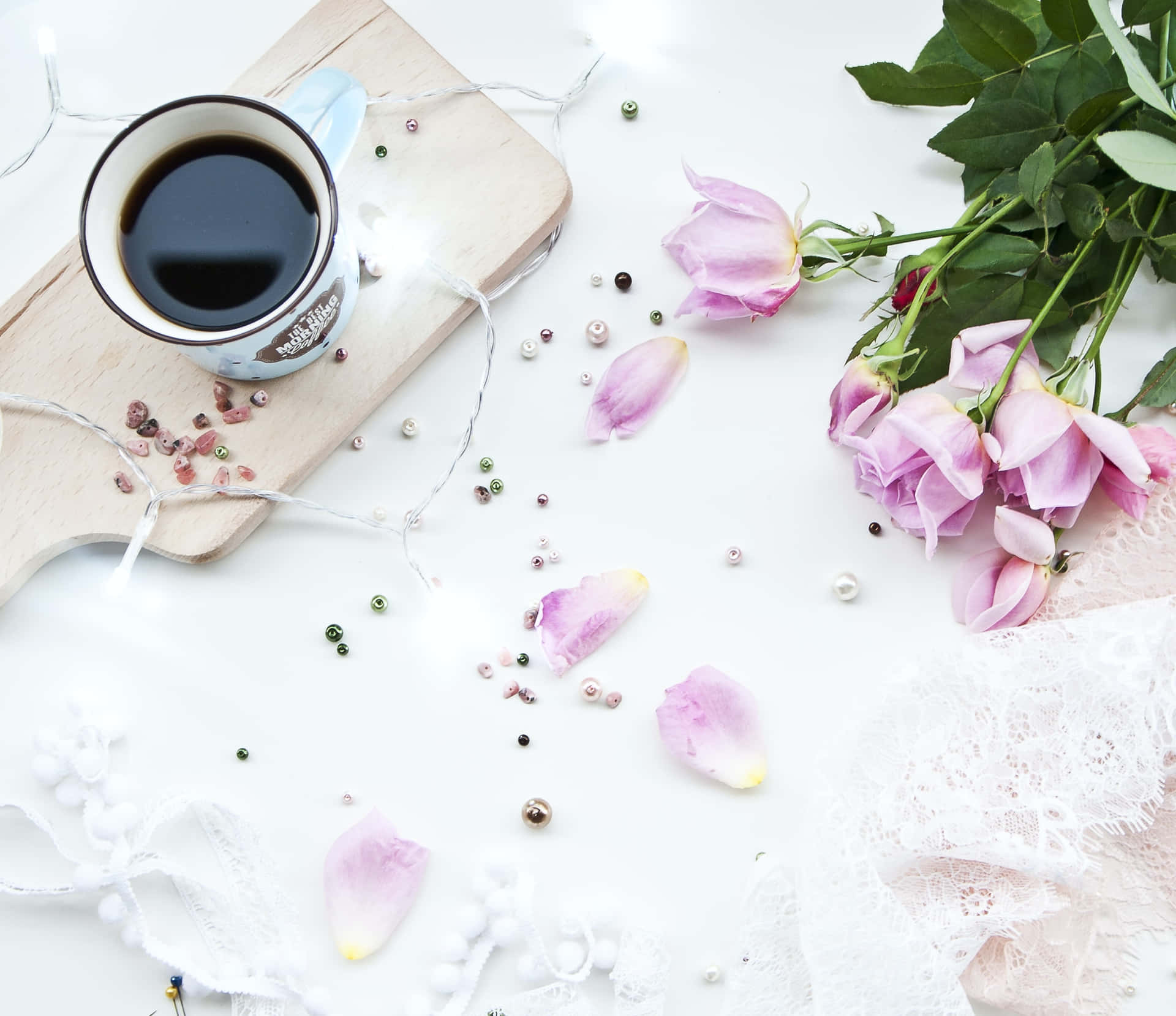 a cup of coffee and roses on a white table