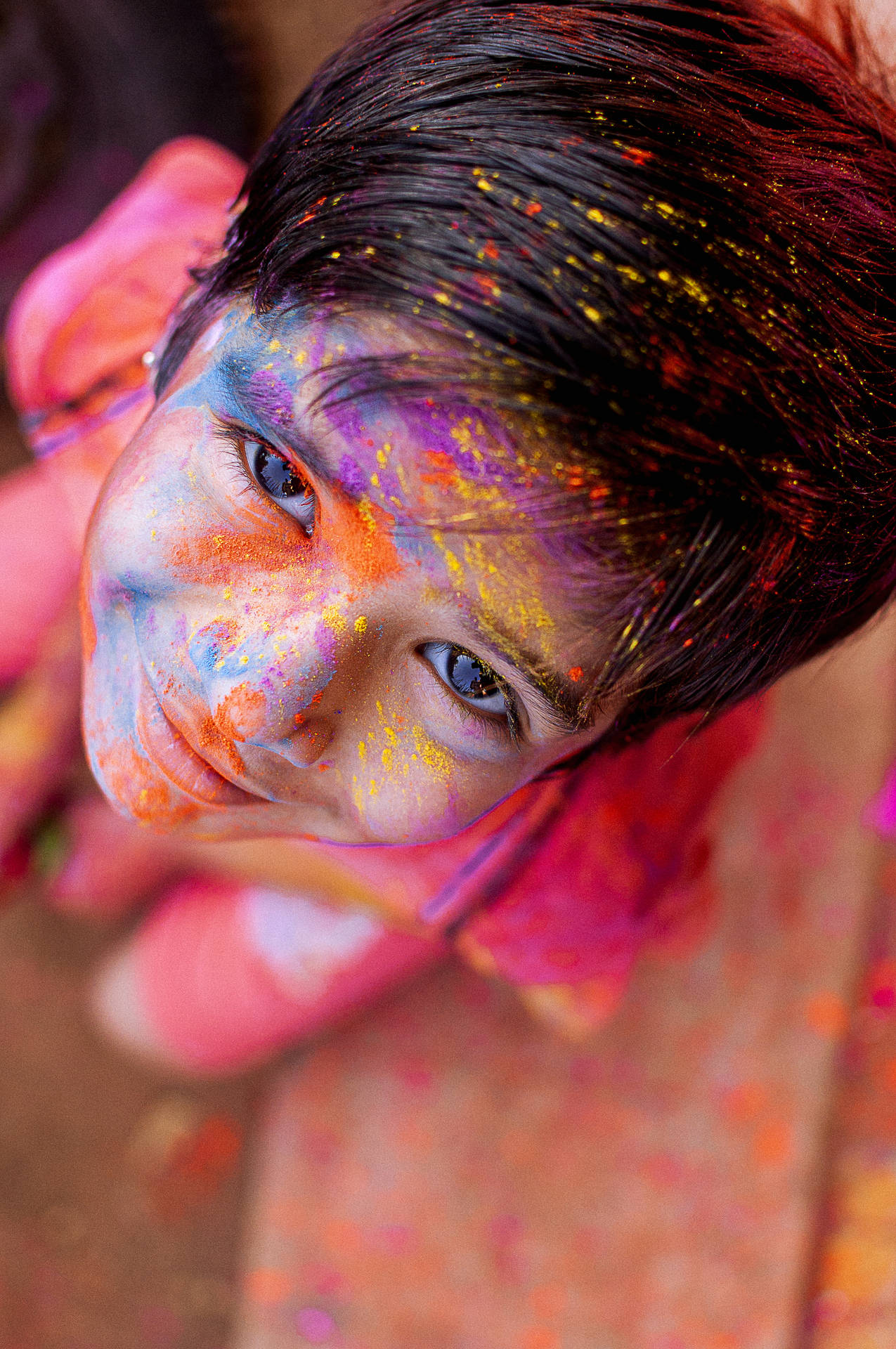 Capturing the Spirit of Holi - Child Joyfully Covered in Holi Colours Wallpaper