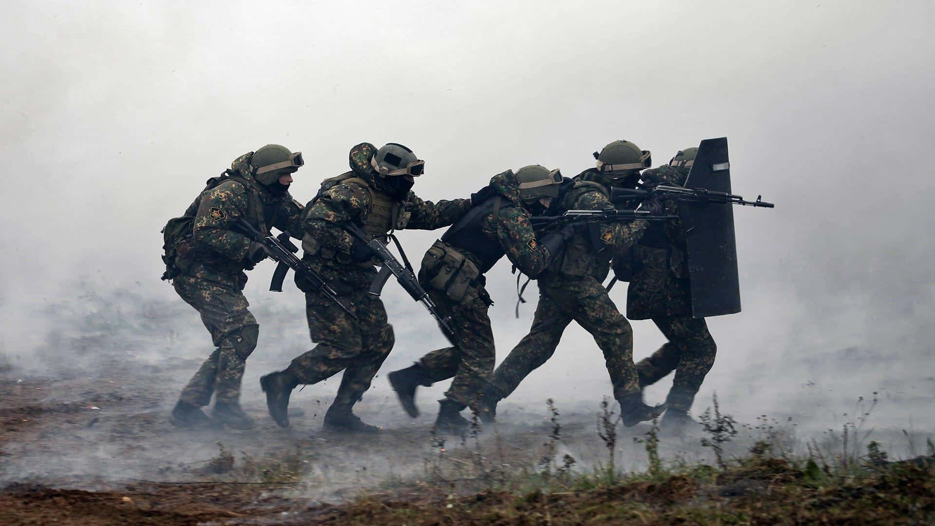 A Group Of Soldiers Are Running Through A Field With Smoke