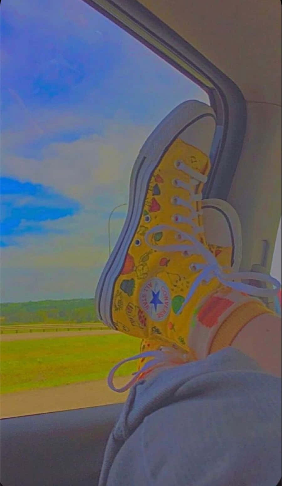 a person's feet are sitting in a car with yellow converse shoes