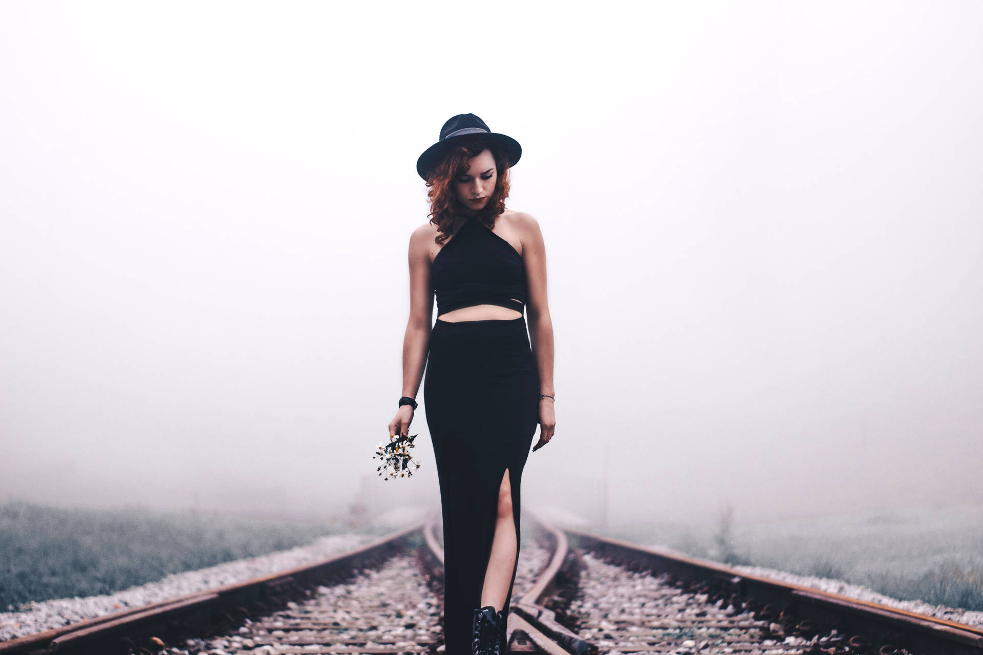 A confident young woman stands in the middle of a empty train railway Wallpaper