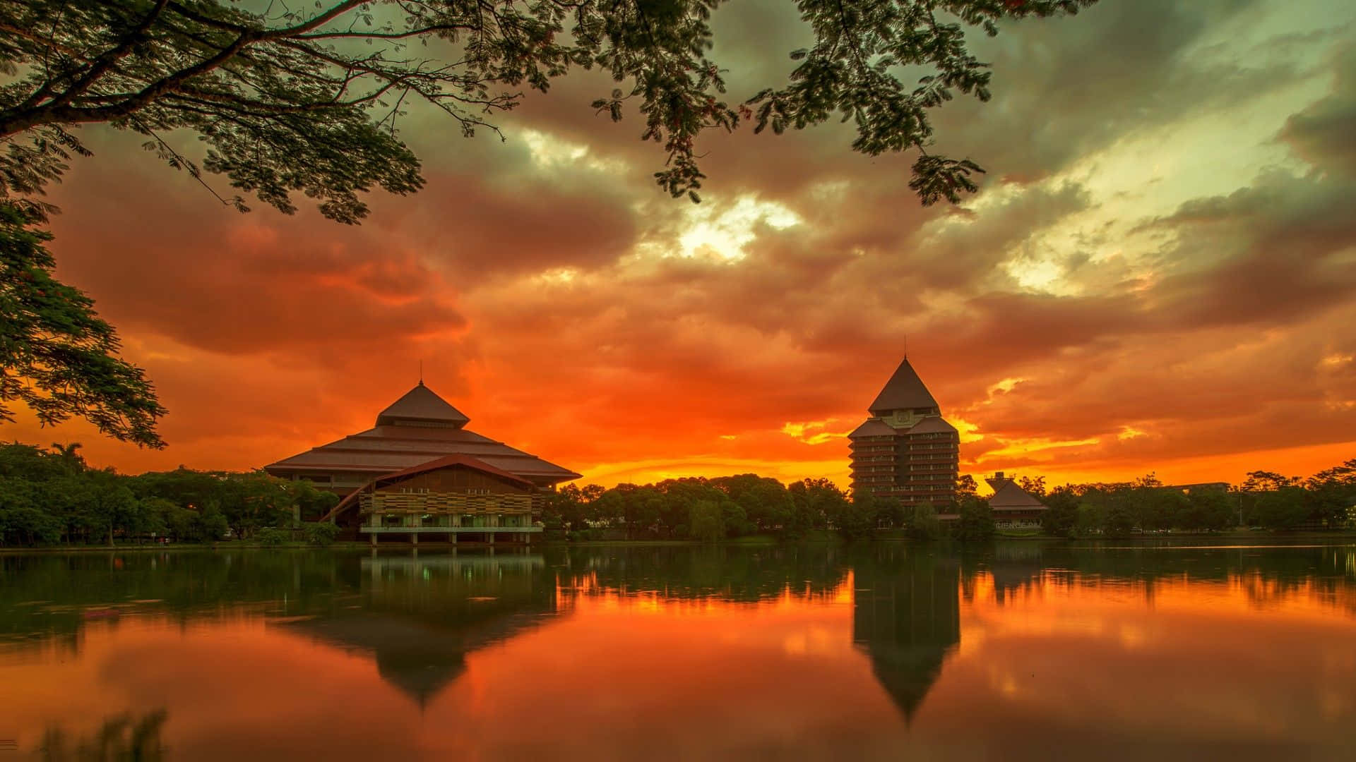 A Sunset Over A Lake With A Tower In The Background