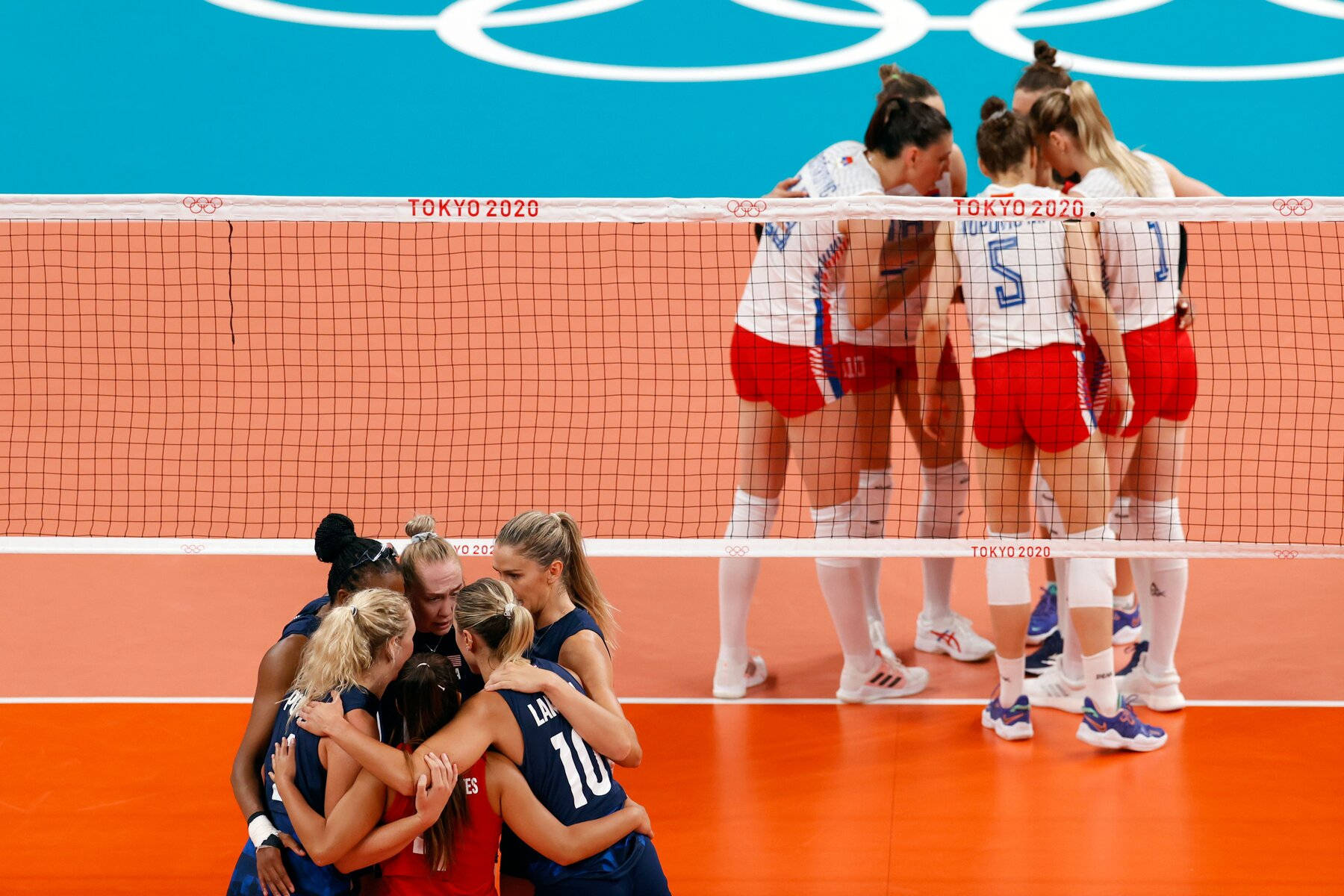 A Group Of Volleyball Players Huddle Around The Net Wallpaper