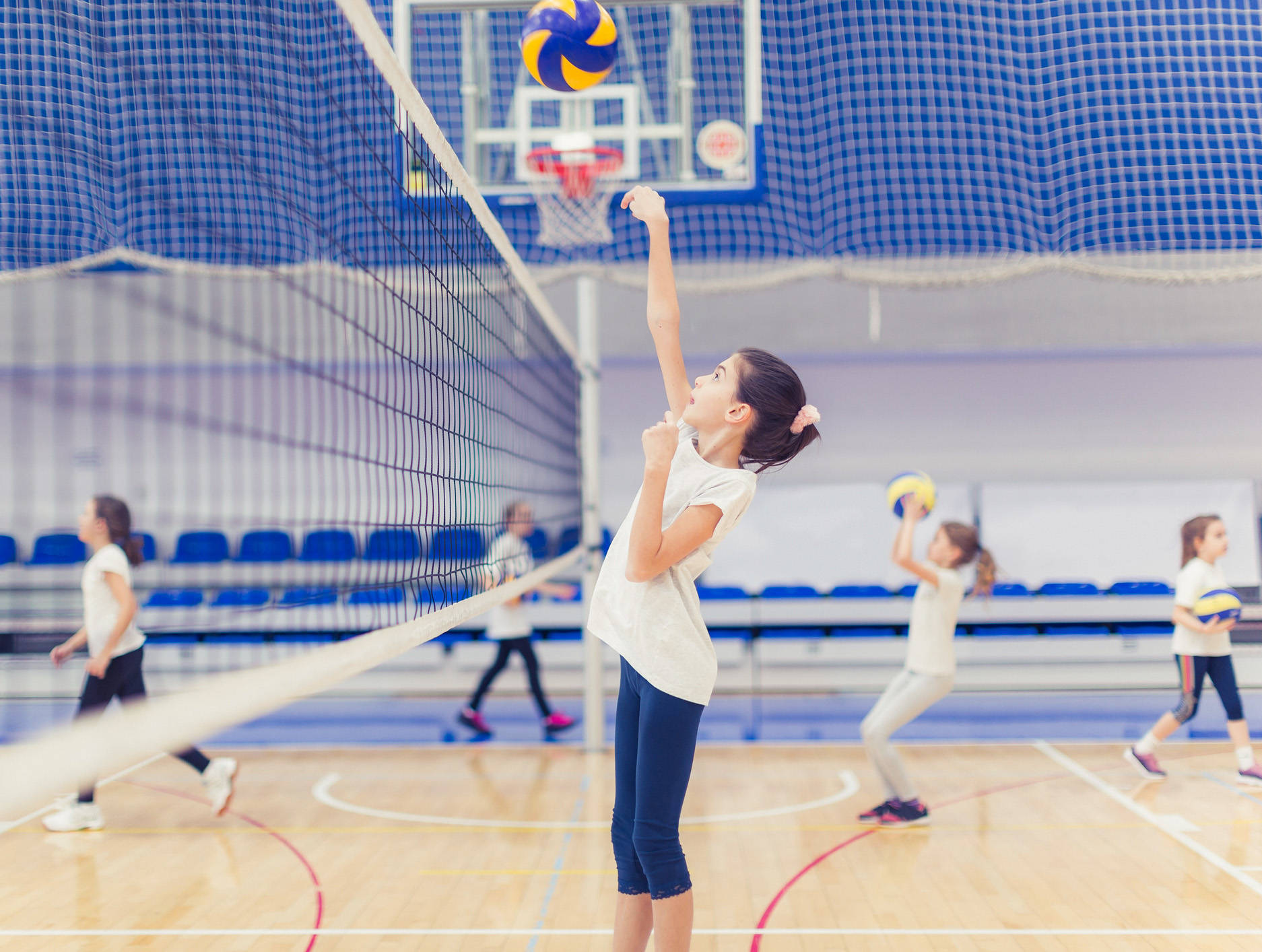 Unge piger spiller volleyball i et gymnasium Wallpaper