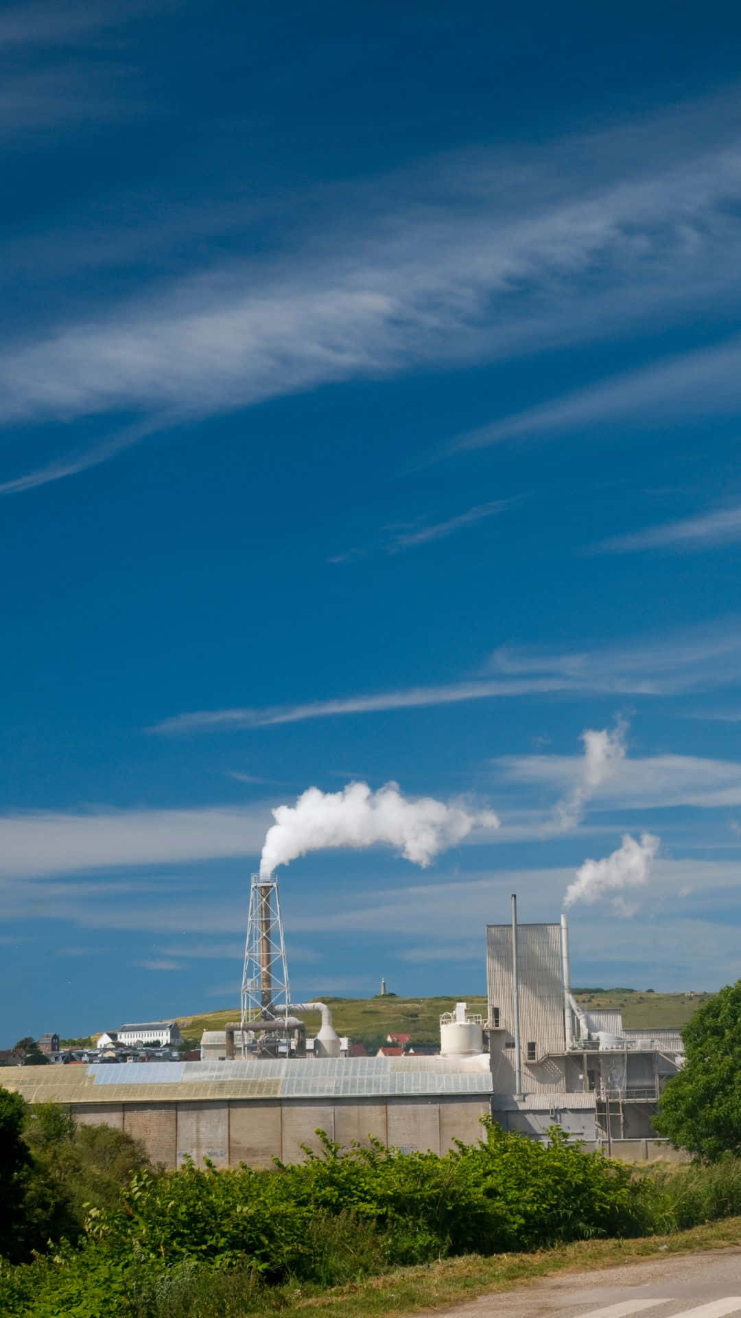 Industrial Facility Emitting Smoke Under Blue Sky Wallpaper