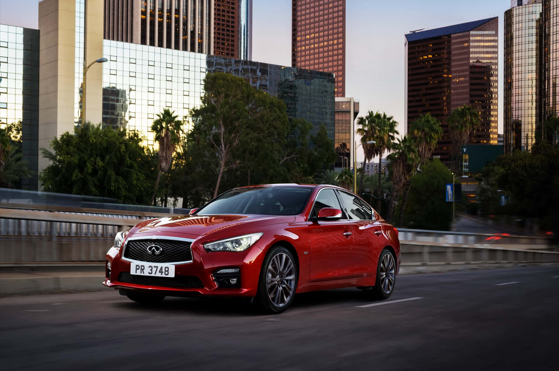 The Red Infiniti Q50 Is Driving Down The Road Wallpaper