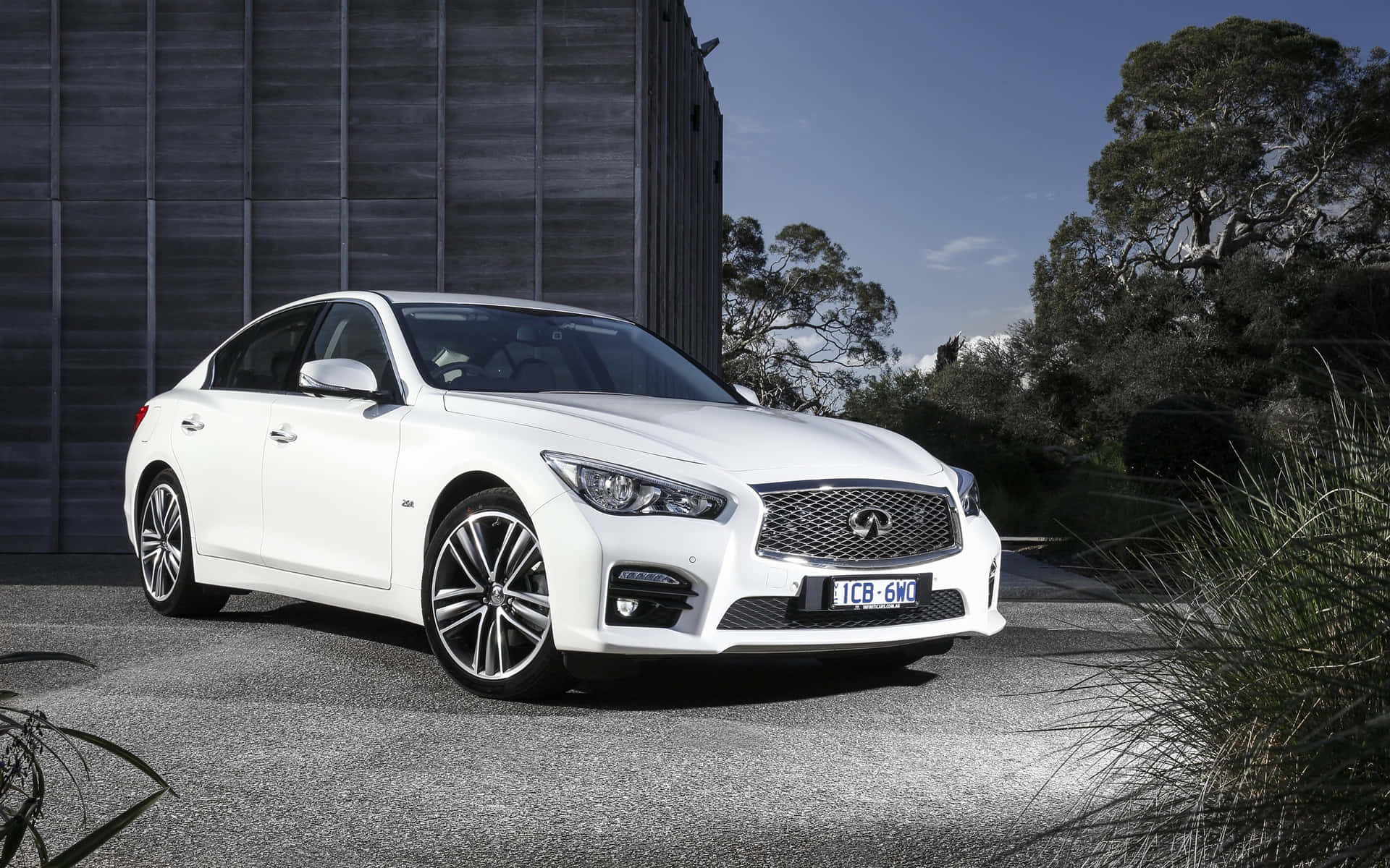 The White Infiniti Q50 Is Parked In Front Of A Building Wallpaper