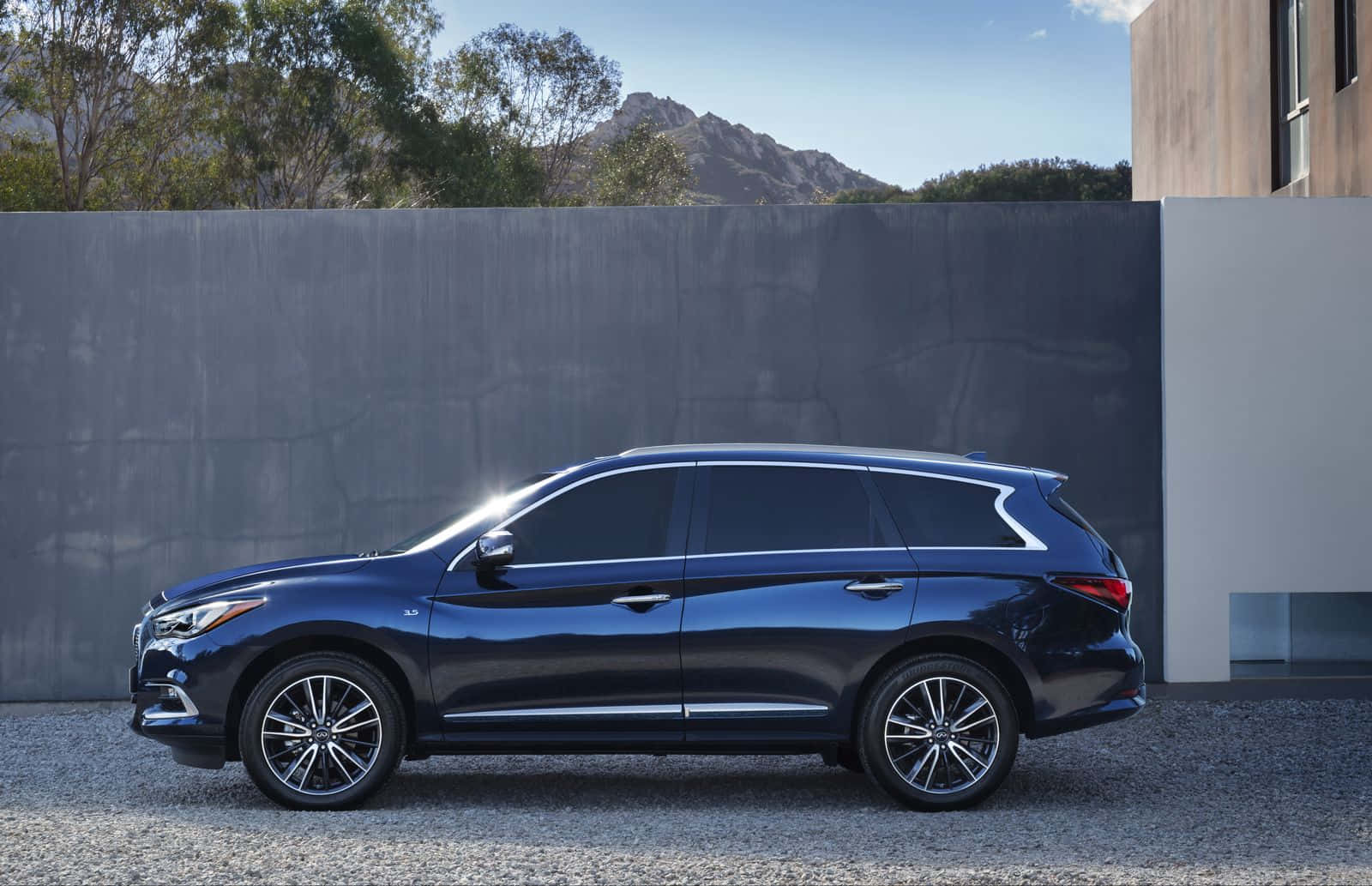 Elegant Infiniti QX60 driving on a picturesque road Wallpaper