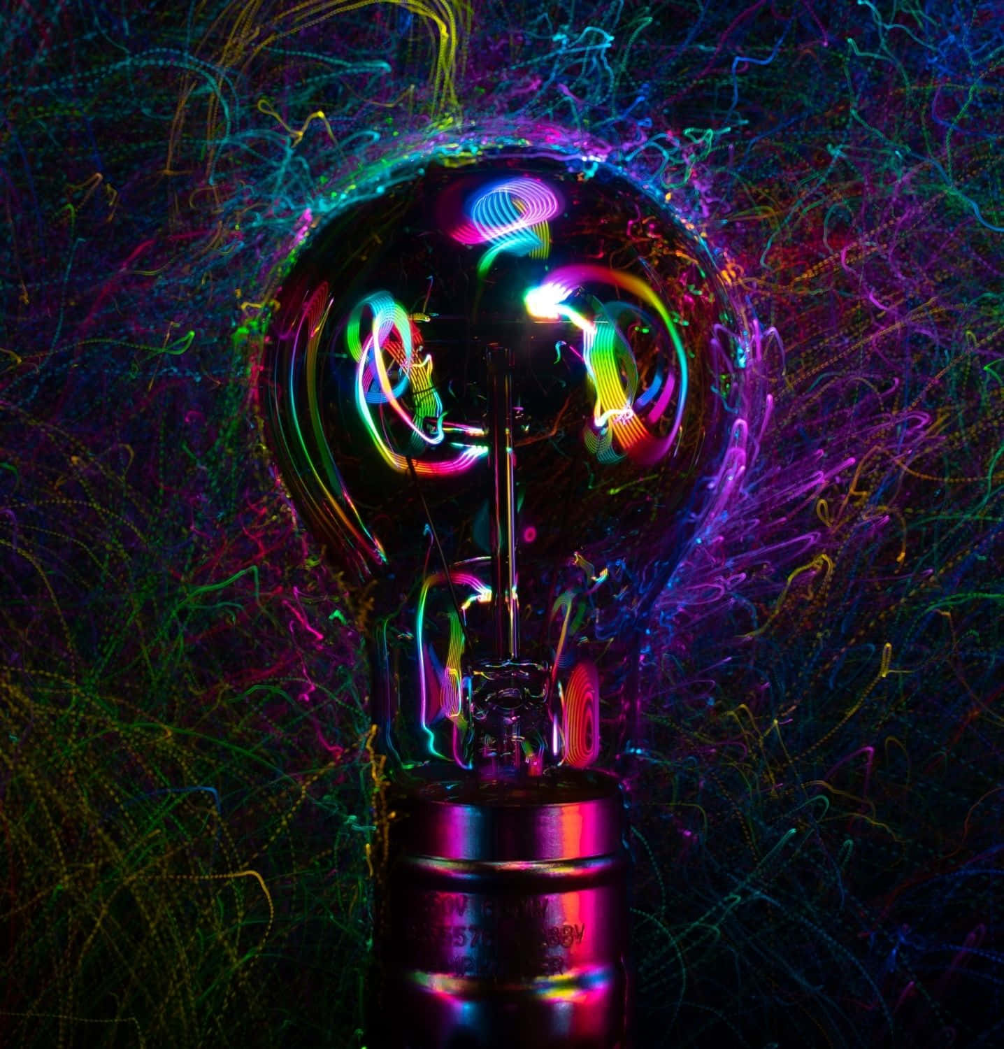 A light bulb illuminating with colorful gears and cogs inside Wallpaper