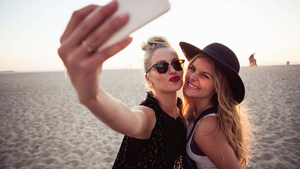 Tvåkvinnor Tar En Selfie På Stranden