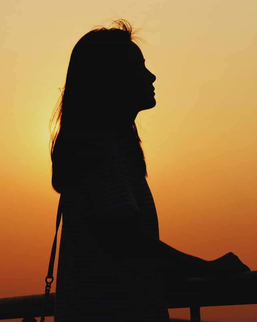 a woman silhouetted against the sunset