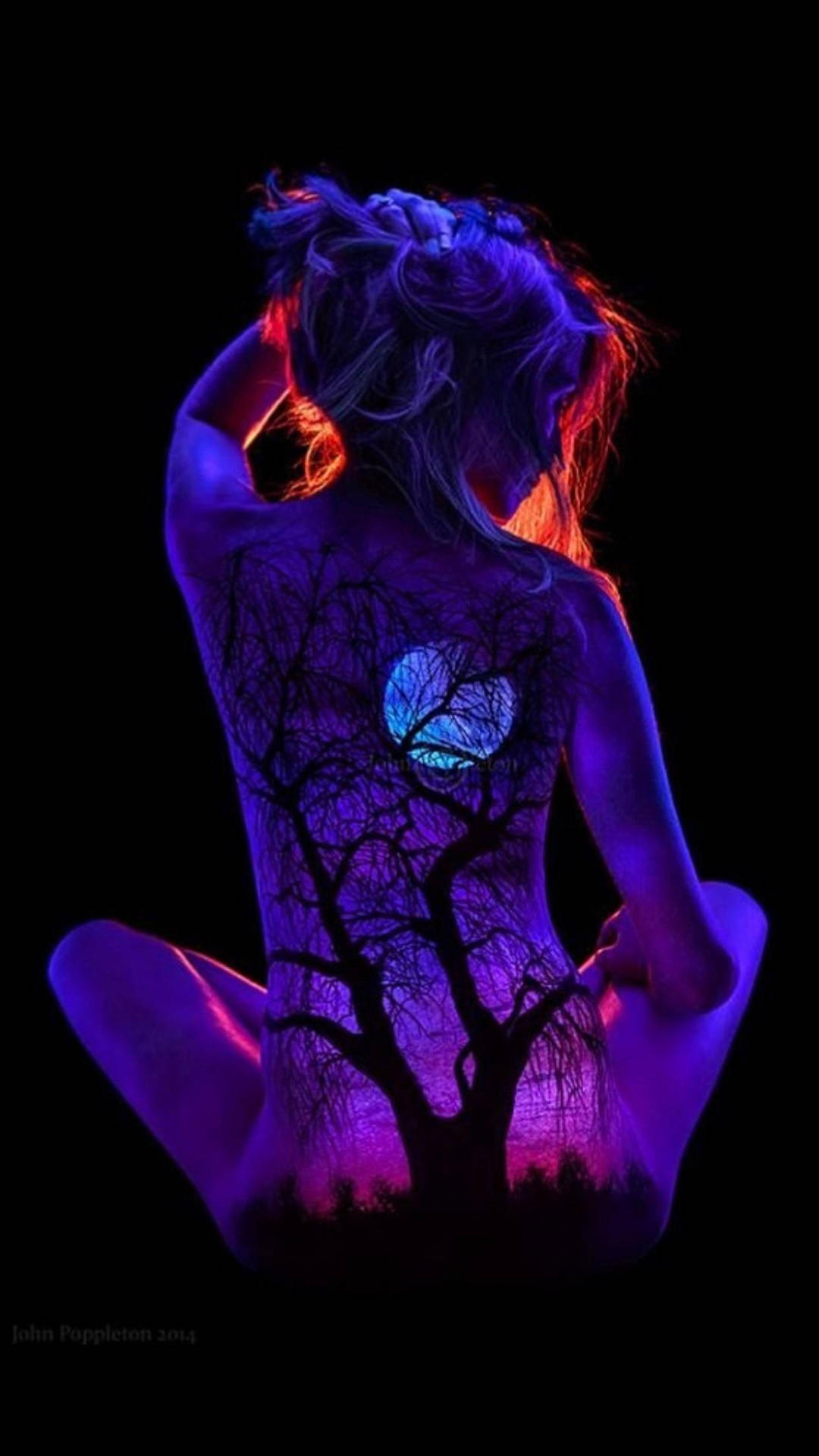 En kvinde sidder i mørket med et lysende træ på ryggen Wallpaper