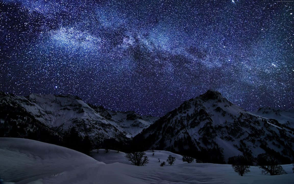 A Mountain Range With Snow Covered Mountains And Stars Above Wallpaper