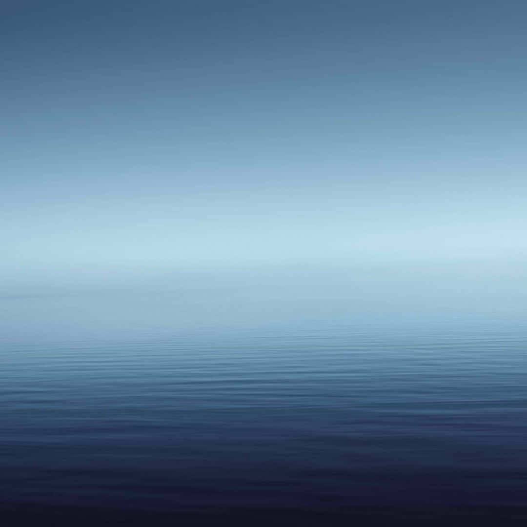En blå himmel med en rolig ocean Wallpaper