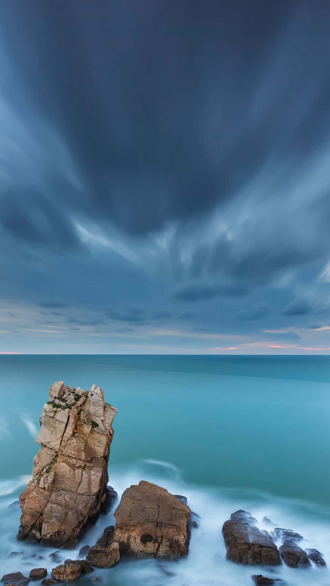 En klippeformation med et mørkt himmel og ocean i forgrunden. Wallpaper