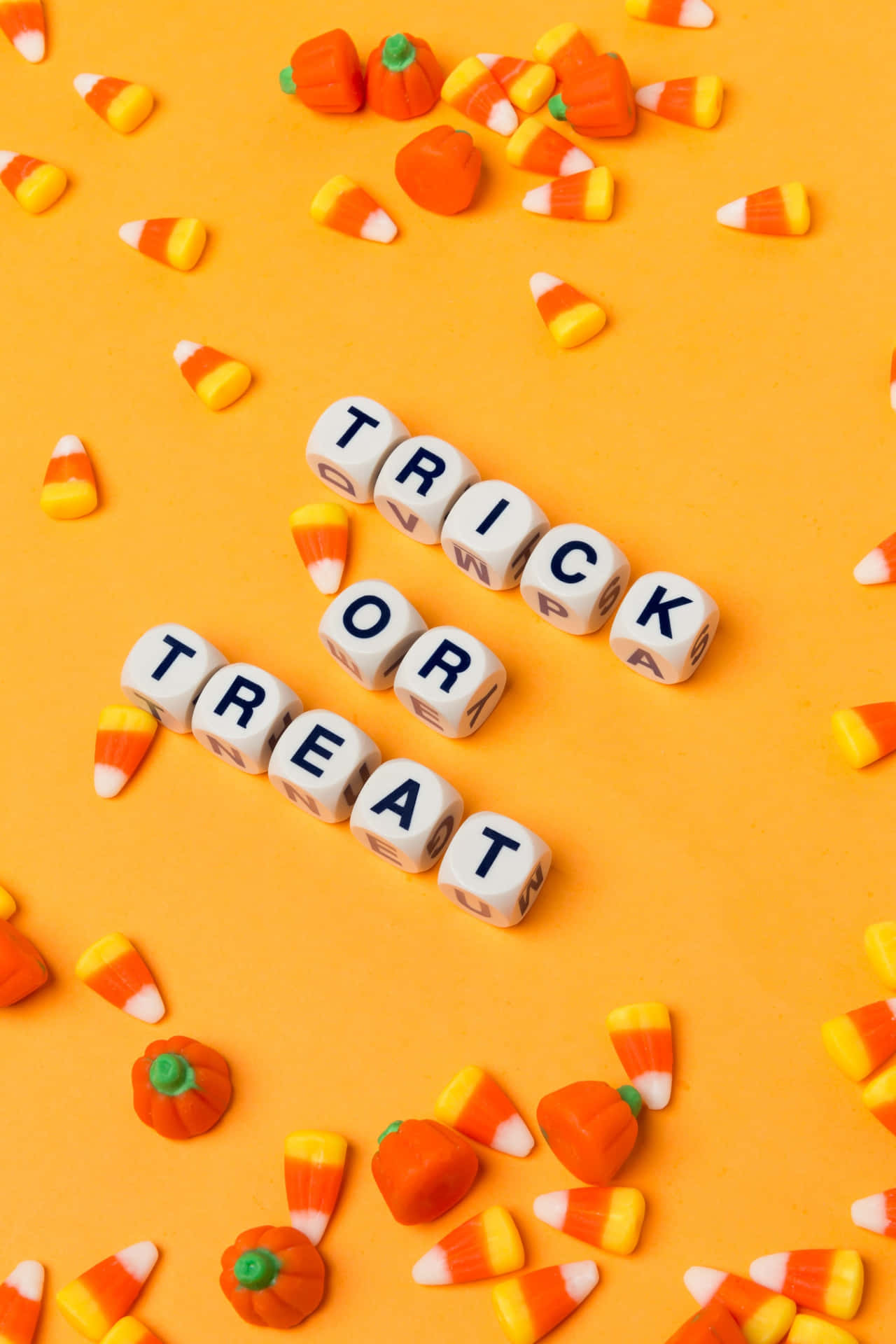 A Halloween Candy Corn And Trick Or Treat Letters On An Orange Background