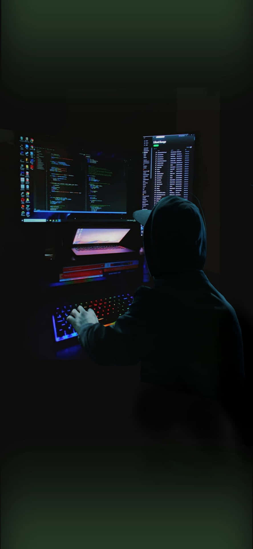 En mand sidder ved en computer i mørket.