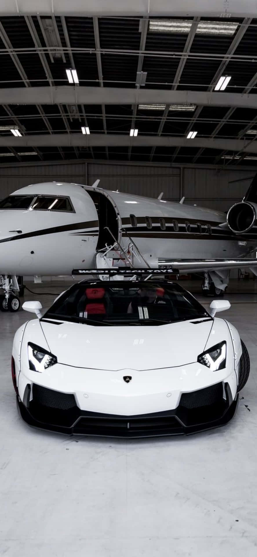 A White Car Parked In Front Of A Jet