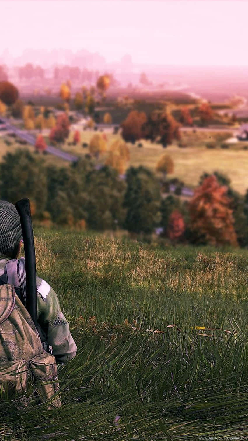 A Man Is Sitting In A Field With A Backpack