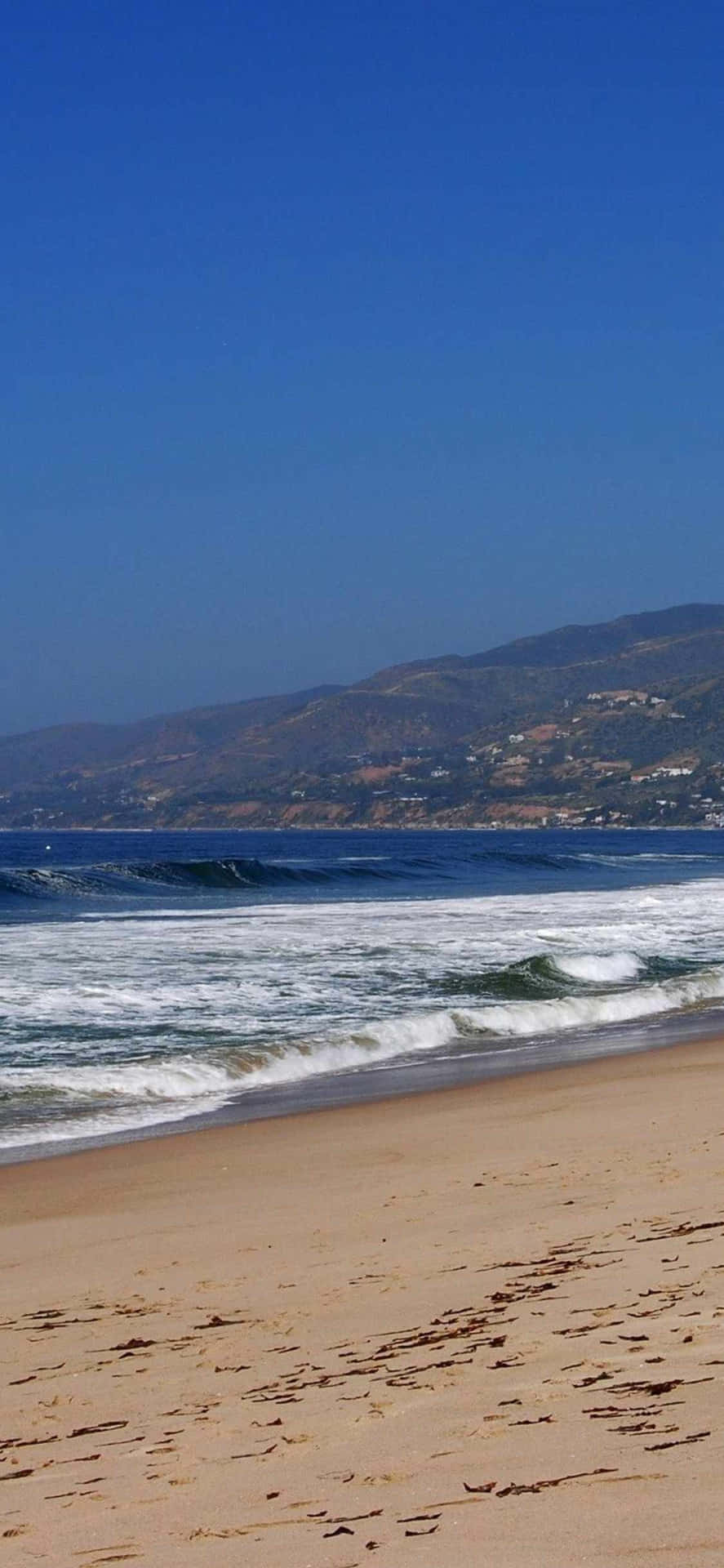 Unhombre Está Caminando En La Playa Con Una Tabla De Surf