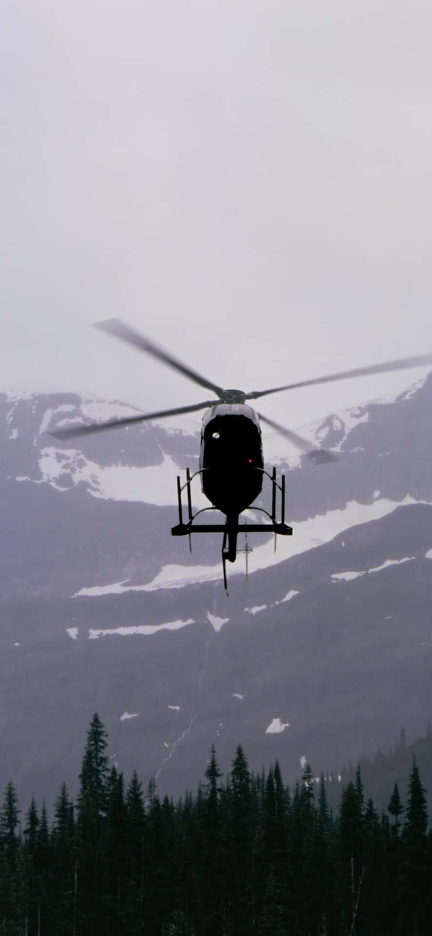 A Helicopter Flying Over A Mountain Range