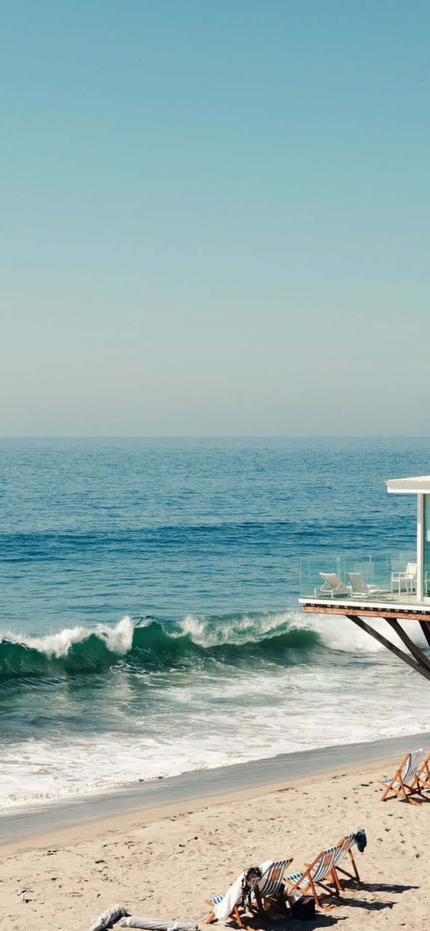 Sfondoiphone Xs Max Malibu Con Onde Che Si Infrangono Vicino A Una Casa Sulla Spiaggia