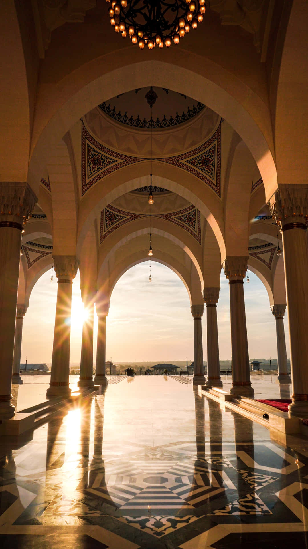 A Large Pool With Arches And A Sun Setting Behind It